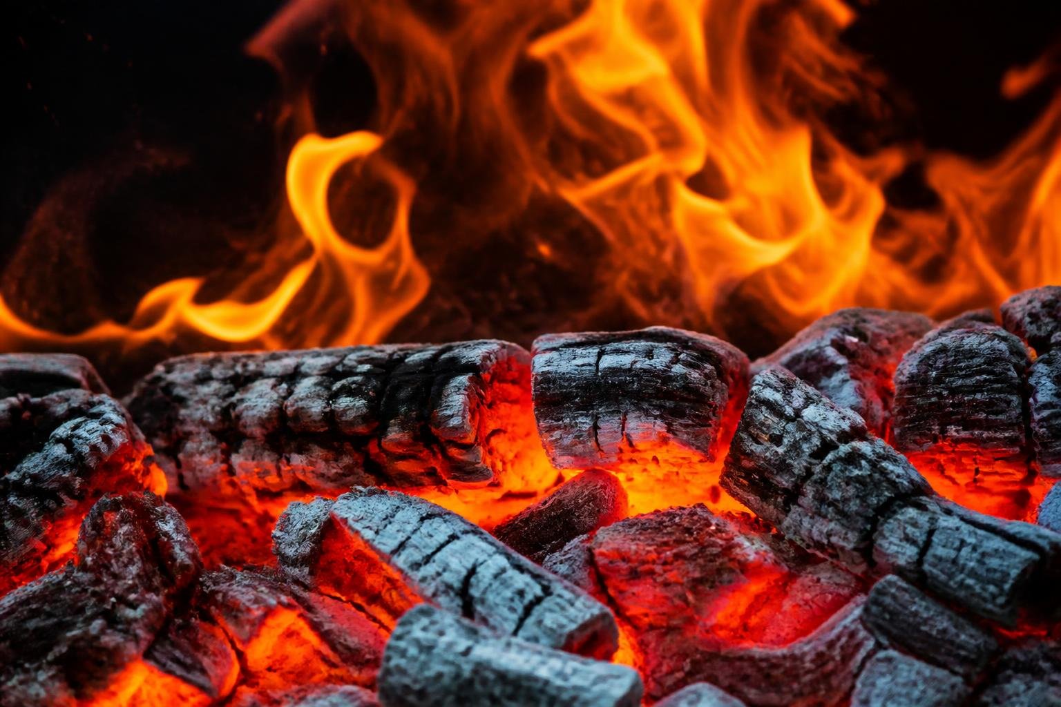 Braises rougeoyantes d'un feu de bois avec flammes vives en arrière-plan