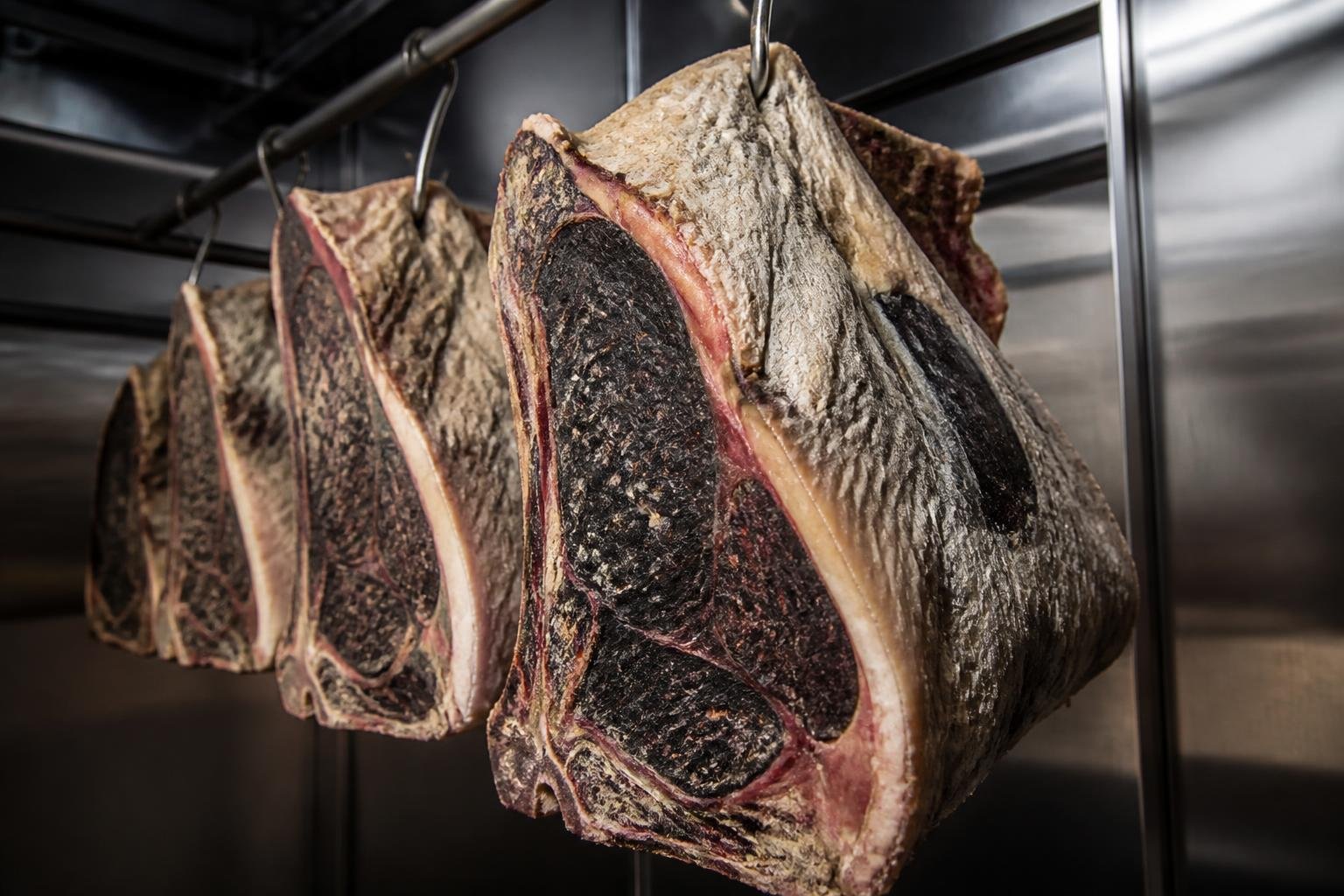 Viande de bœuf maturée suspendue dans une chambre froide, montrant la croûte caractéristique de maturation à sec
