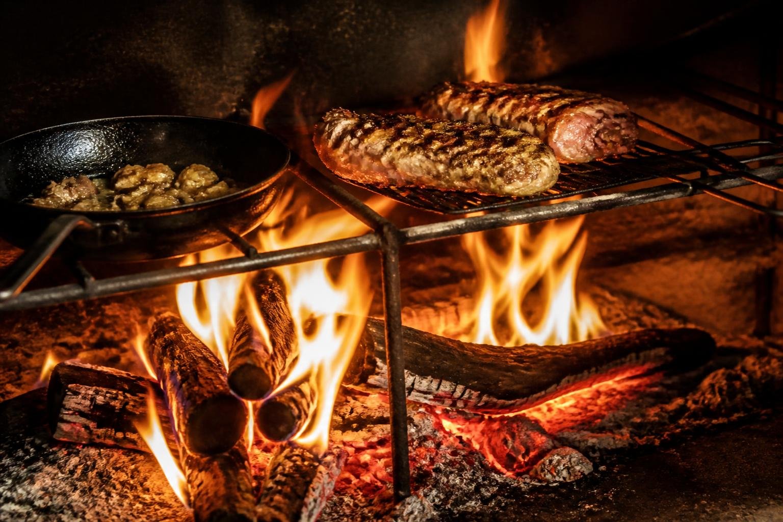 Flammes d'un feu de bois dans une cuisine ouverte, avec braises rougeoyantes